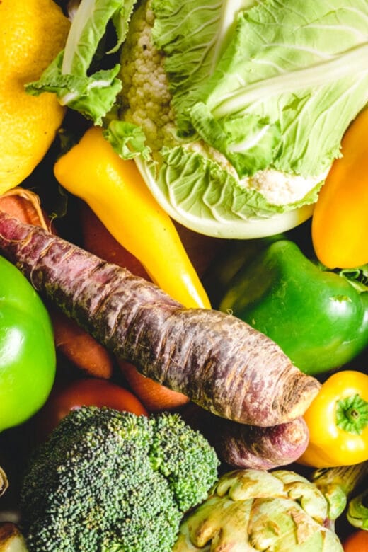 a pile of various vegetables such as lettuce, green and yellow bell peppers, and broccoli