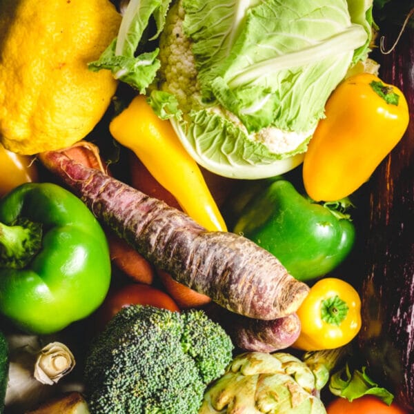 a pile of various vegetables such as lettuce, green and yellow bell peppers, and broccoli