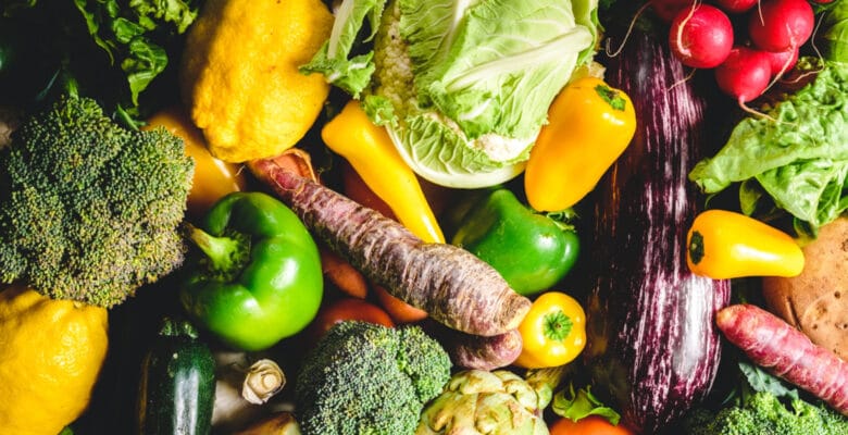 a pile of various vegetables such as lettuce, green and yellow bell peppers, and broccoli