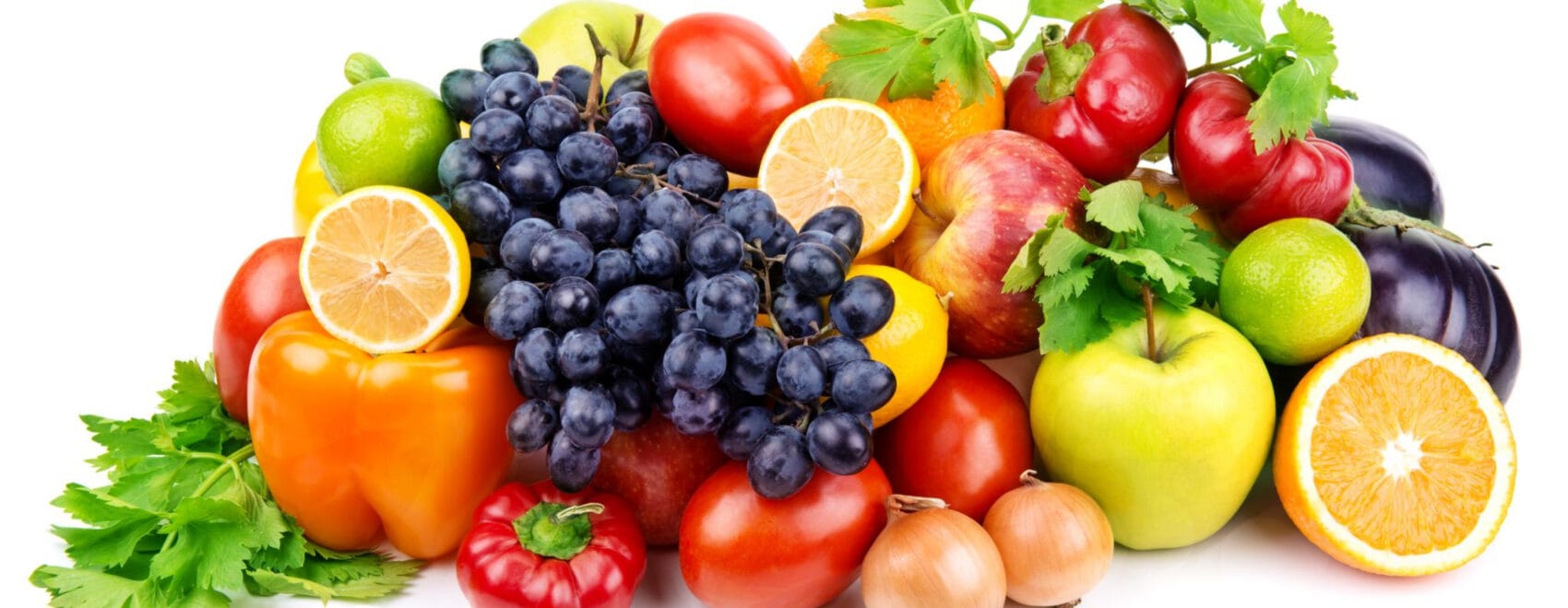 a pile of assorted fruits and vegetables including bell peppers, sliced oranges and lemons, apples, tomatoes, onions, grapes, limes