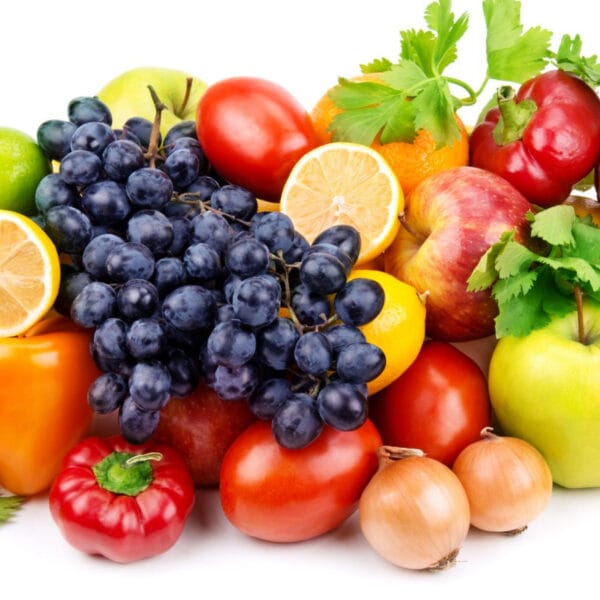 a pile of assorted fruits and vegetables including bell peppers, sliced oranges and lemons, apples, tomatoes, onions, grapes, limes
